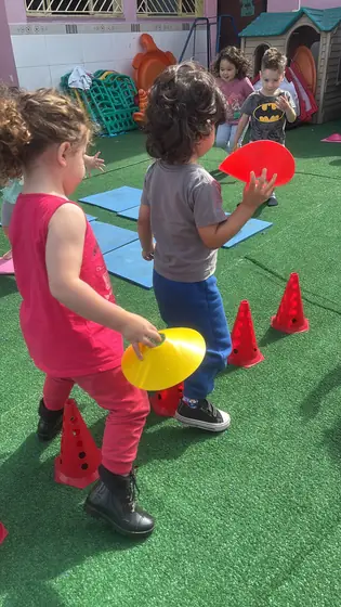 Aula de Little Kickers no gramado, com bolas e circuito de cones